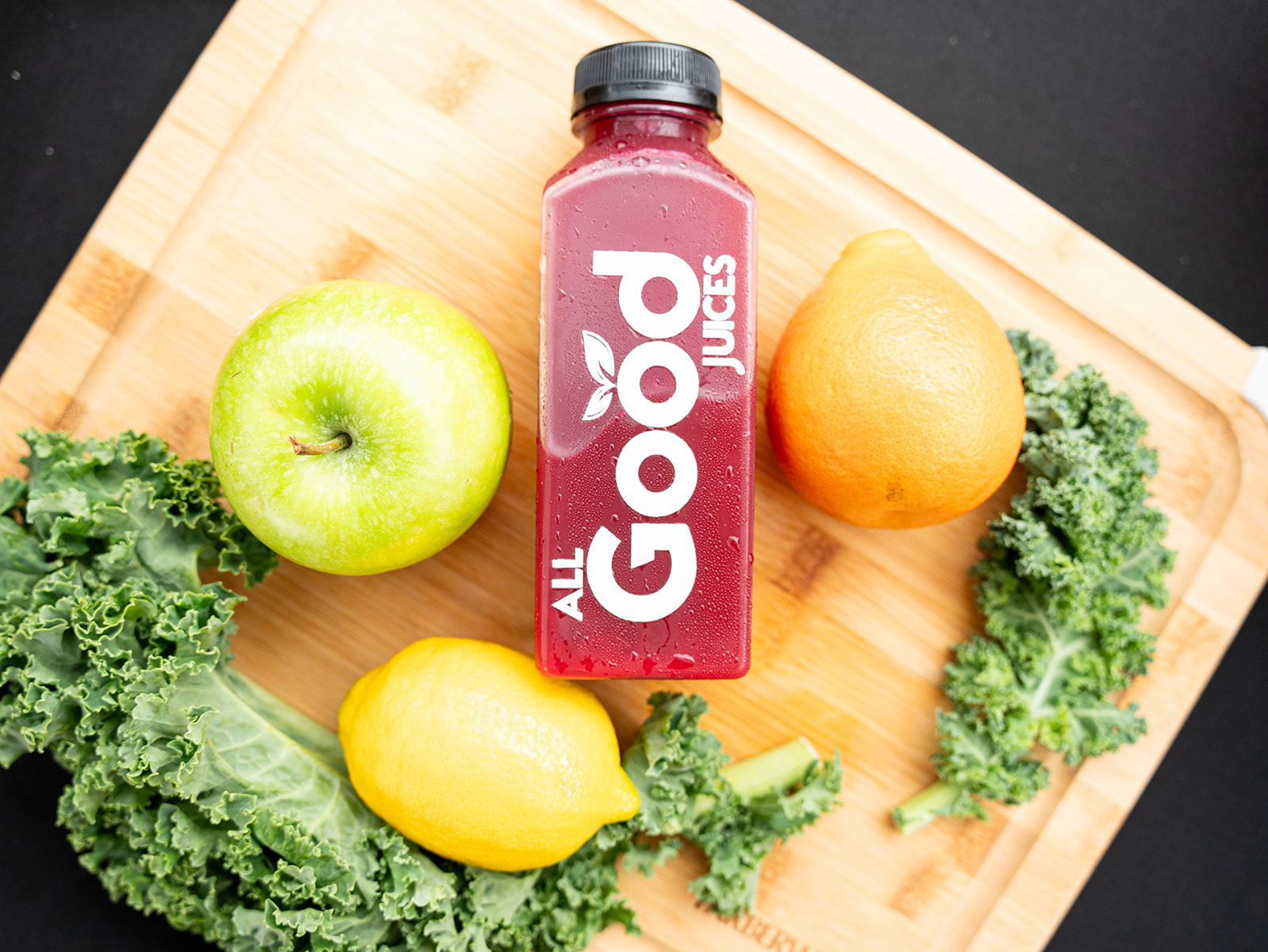 Flat lay of a juice bottle with apple, lemon and kale
